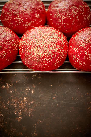 Fresh baked red homemade burger buns with sesame top view. Placed on metal grill.の写真素材