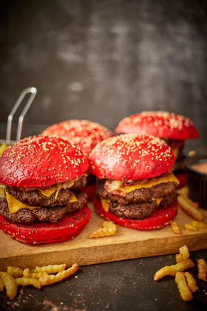 Set of four homemade giant double becon cheese burgers. Served with french fries on wooden board.の写真素材