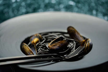 Seafood black spaghetti pasta with clams served on black plate on dark stoneの写真素材