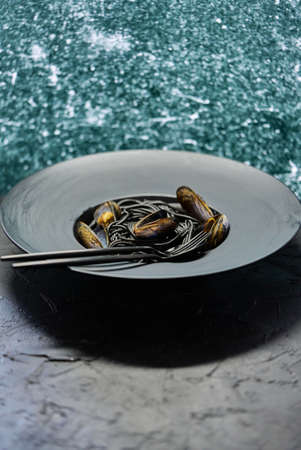 Seafood black spaghetti pasta with clams served on black plate on dark stoneの写真素材