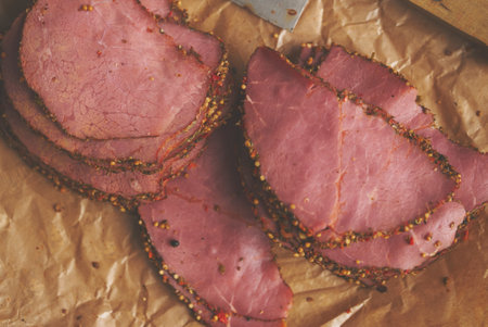 Delicious peppered roast beef pastrami slices on paper with grains of coloured pepperの写真素材