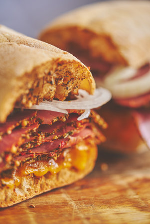 Thin cut pastrami sandwhich with delicious meet on baguette bread with chedder cheese, onionの写真素材