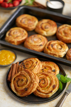 Delicious, fresh baked cinnamon buns served on black ceramic plate. With various sidesの写真素材