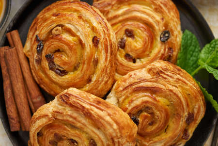 Close up of Sweet cinnamon roll cake with raisins filling served on the black plateの写真素材