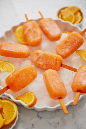 Homemade, juicy, orange ice creams. Placed on a white plate with ice cubesの写真素材