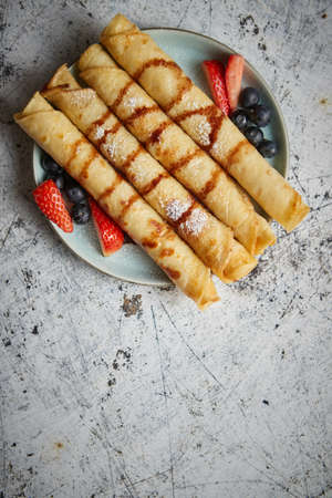 Plate of delicious crepes roll with fresh fruits and chocolateの写真素材