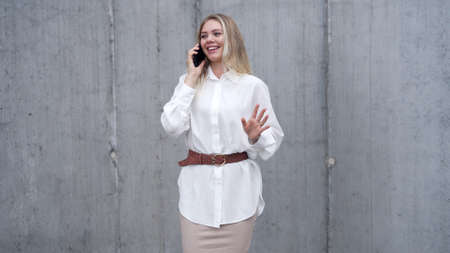 Cheerful businesswoman speaking on smartphone on streetの写真素材