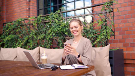 Happy freelancer using smartphone in cafeteriaの写真素材