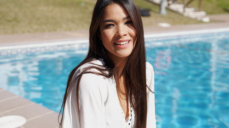 Cheerful ethnic woman near swimming poolの写真素材