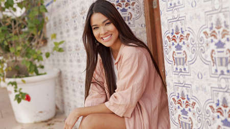 Smiling ethnic woman sitting on streetの写真素材