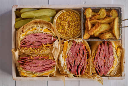 Enormous sandwiches with pastrami beef in wooden box. Served with baked potatoes, picklesの写真素材