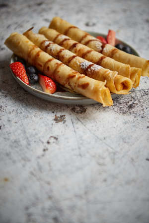 Plate of delicious crepes roll with fresh fruits and chocolateの写真素材