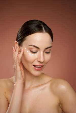 Smiling woman with makeup touching faceの写真素材