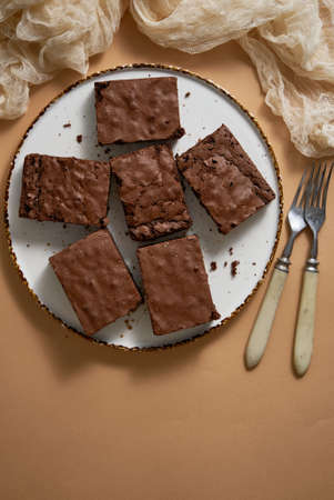 Delicious homemade chocolate brownies served on white plate over beige backgroundの写真素材