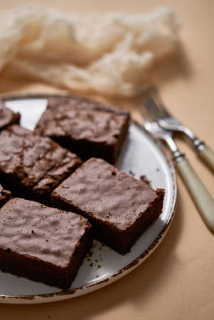 Delicious homemade chocolate brownies served on white plate over beige backgroundの写真素材