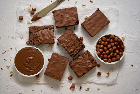 Fresh homemade chocolate brownie served with hazelnuts and melted creamの写真素材