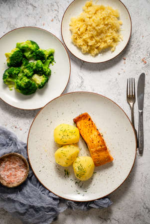 Homemade baked salmon served with popatoes, broccoli and sauerkrautの写真素材