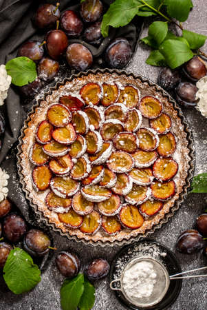 Homemade delicious plum tart with with sugar powder placed on the tableの写真素材