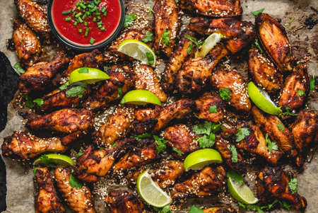 Baked delicious homemade chicken wings with fresh herbs, tomato dip and limeの写真素材