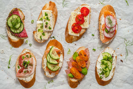Variety of small sandwiches with cream cheese, vegetables and salami.の写真素材