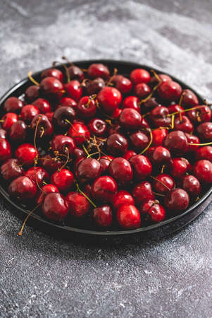 Sweet fresh Cherry on a plate on a stone backgroundの写真素材