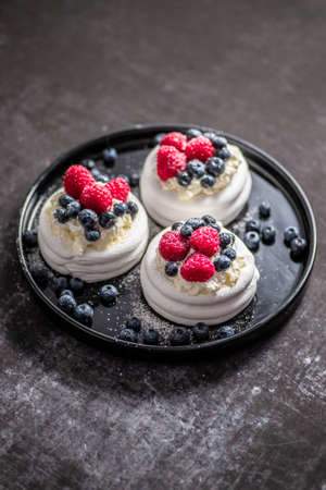 Mini Pavlova cakes topped with berries and mascarpone cheeseの写真素材