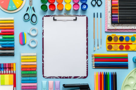 Colorful school supplies placed on blue background with white plain paper in the middle