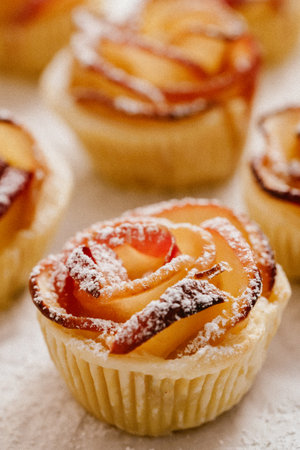 Apple rose puff pastries sprinkled with powdered on baking paper