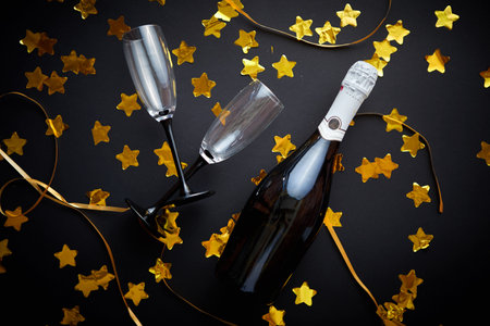 Glasses and bottle of champagne with golden serpentines and confettiの写真素材