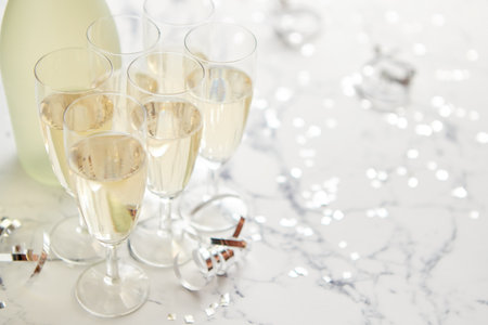Champagne glasses and bottle placed on white marble backgroundの写真素材