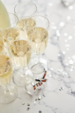 Champagne glasses and bottle placed on white marble backgroundの写真素材