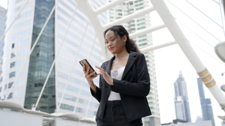 Asian executive working woman holding and using mobile phone in the streetの写真素材
