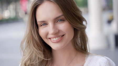 A smiling young adult with long hair in a headshot portraitの写真素材