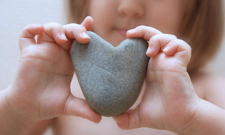 Child's hands hold heartの写真素材