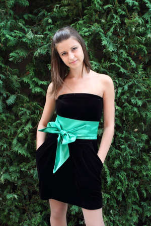 Portrait of the young girl in the black dress on the green background の写真素材