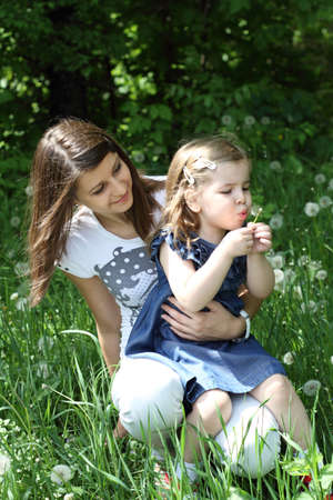  Two girls play on the glade with dandelionsの写真素材