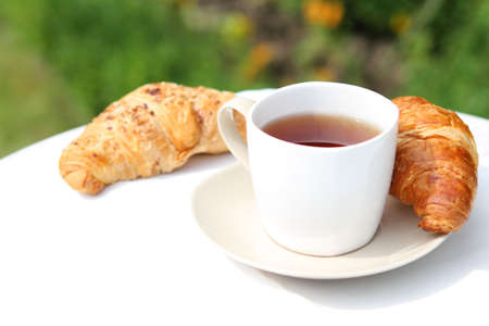 Tea and croissants on the table in the gardenの写真素材