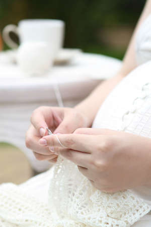 Pregnant young woman in white knitting in the gardenの写真素材