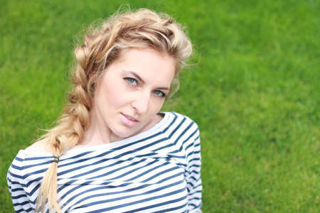Portrait of the blond girl on the grass backgroundの写真素材