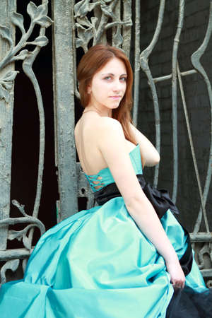 Romantic girl in the beautiful dress near the fenceの写真素材