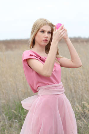Beautiful blond girl in pink on the fieldの写真素材