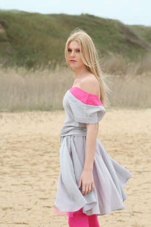 Beautiful romantic girl on the yellow sand in the windy dayの写真素材