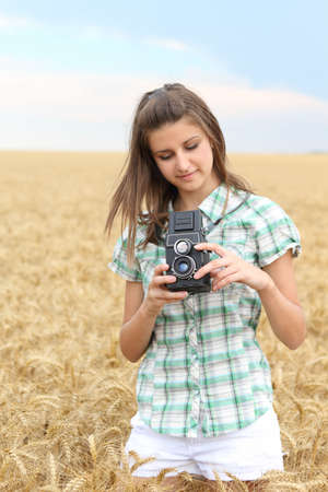 Young brunette girl in the wheat field with old TLR cameraの写真素材