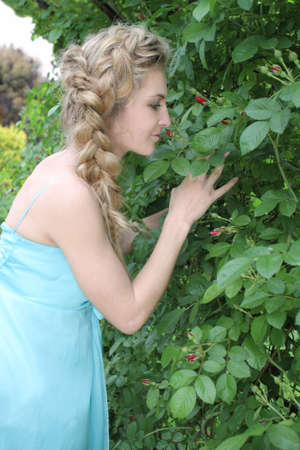 Young attractive blond girl in the blue dress in the gardenの写真素材
