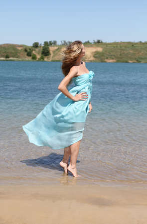Romantic girl in the beautiful dress near the waterの写真素材