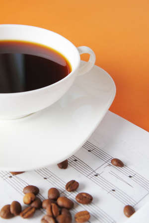 Coffee beans and cup of coffee on a musical backgroundの写真素材