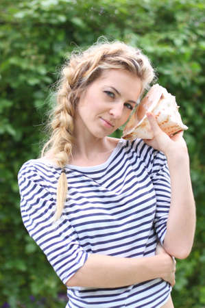 Young attractive blond girl listen to a shellの写真素材