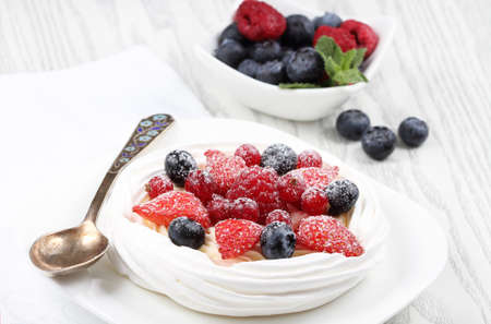 Fresh meringue with thick cream and fruits on a plateの写真素材