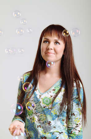 Smiling brunette girl looking at soap  bubblesの写真素材