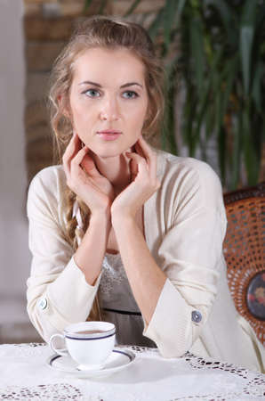Young blond girl with tea in the cafeの写真素材